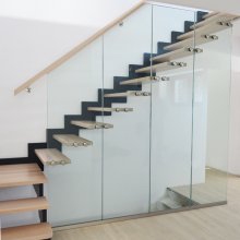Moderné, dizajnové schodisko so stupňami kotvenými v skle, ktoré prechádza do zábradlia. Sklo zároveň slúži ako zábrana pre otvor pod schodiskom.