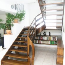 Celodrevené ohýbané schodisko s tvarovým sĺpom na nástupe a knižnicou. Rovinka